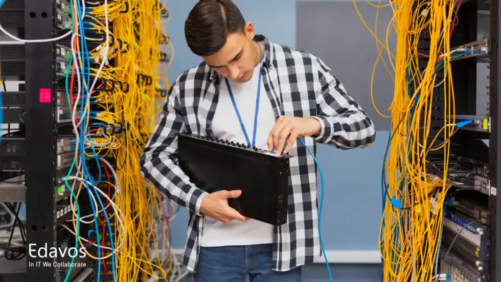 Teknisi memeriksa kabel jaringan di server room untuk mengatasi masalah Wi-Fi kantor yang lemot.